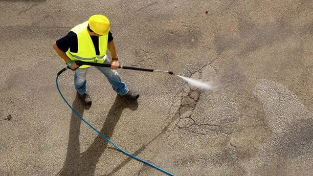 A pressure washer being used to clean a paved surface